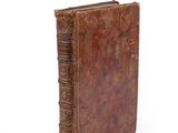 an old brown book sitting on top of a white surface