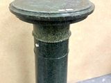 a green pedestal with a black top on the floor