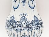 un vase bleu et blanc muni d'une anse et posé sur un socle