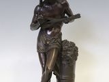 statue représentant une femme tenant un panier de raisins, posée sur un socle en bois
