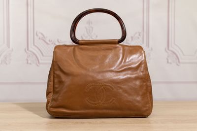 brown leather handbag with bamboo handle on wooden table