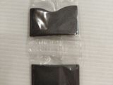 two pieces of black plastic on a white surface