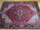 un tapis oriental posé sur un parquet, avec une chaise à l'arrière-plan