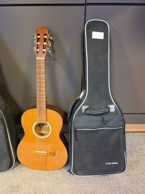 three guitars are lined up against a wall with a guitar case