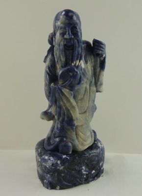 une statue bleue et blanche représentant un homme tenant un sac