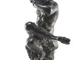 statue of a man sitting on a rock with a hat on his head