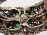 a close up of a person holding a bracelet with many different colored stones