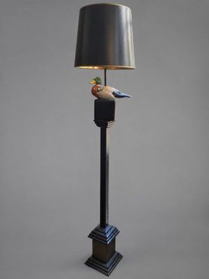 une lampe noire surmontée d'un oiseau, à côté d'un abat-jour
