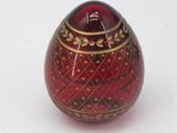 a red and gold vase sitting on a white surface