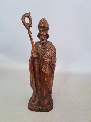 wooden figurine of a priest holding a staff and a cross