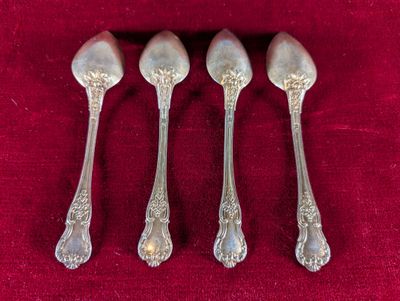 four silver spoons on a red cloth with a red background