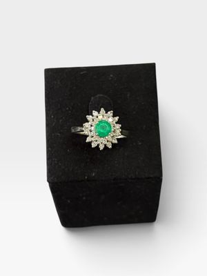 un gros plan d'une bague dans une boîte noire posée sur une surface blanche