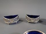 three pieces of silver and blue glass sitting on top of a table