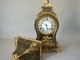 une horloge en or posée sur une table, à côté d'un livre