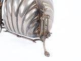 a silver purse sitting on a stand on a white surface