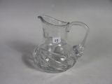 a clear glass pitcher with a handle on a table