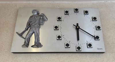 a metal clock with a statue of a man holding a baseball bat