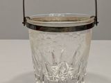 a small glass ice bucket with a handle on a table