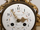 a gold clock with a white face and numbers on it