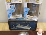 two harry potter figurines sitting on top of a wooden shelf next to a box of harry potter figurines