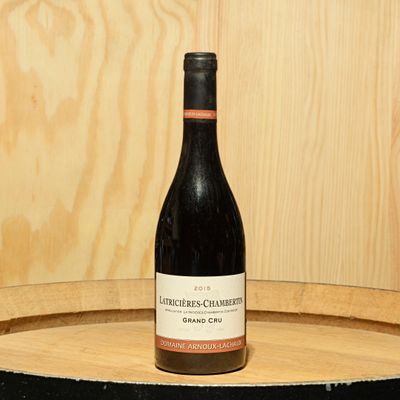 a bottle of wine sitting on top of a barrel