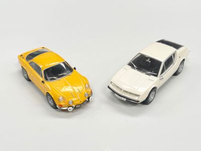 deux voitures jouets assises l'une à côté de l'autre sur une surface blanche