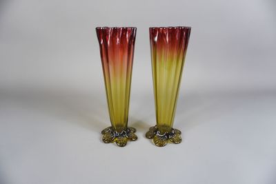 une paire de vases en verre rouge et jaune posés sur une surface blanche
