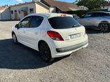 une petite voiture blanche garée sur un parking à côté d'une maison