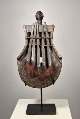 sculpture représentant un instrument de musique posé sur un socle, sur une surface blanche