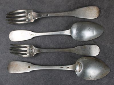 trois cuillères en argent et deux cuillères en argent sur une table