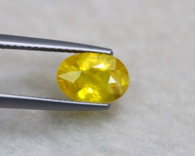 un gros plan d'un diamant jaune tenu par une paire de pinces
