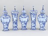 four blue and white vases are lined up against a gray background