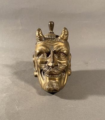 brass statue of a man ' s face with horns and a crown