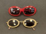 two pairs of red and gold sunglasses sitting on top of a table