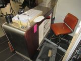 a desk with a chair and a refrigerator in a room