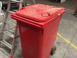 a red trash can sitting next to a step ladder