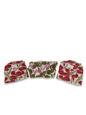 un lot de trois serviettes à motifs floraux rouges et verts sur fond blanc