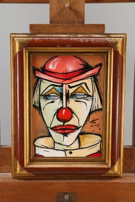 un tableau représentant un clown coiffé d'un chapeau rouge, posé sur un chevalet