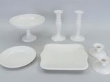 beaucoup de vaisselle blanche et de bougies sur la table