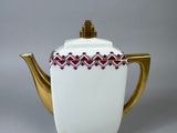 an image of a white teapot with a gold handle and a red and white design