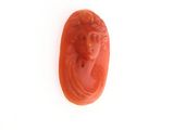 une image représentant un scarabée sculpté de couleur rouge, orné d'un visage de femme