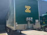 a green semi truck that is parked in front of a building