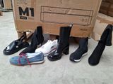 Plusieurs paires de chaussures sont alignées devant un carton.