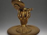 a gold statue of a hand holding a shell on top of a plate