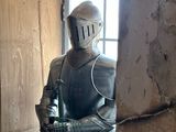 un homme en armure, debout dans une embrasure de porte
