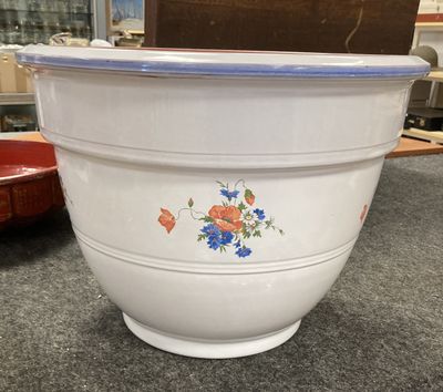 un grand saladier blanc orné de fleurs bleues et rouges