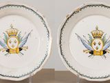 two plates with a crown and two swords on them on a table