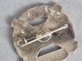 a silver brooch with a metal pin on it