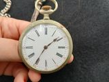 a person holding a pocket watch with a chain around it