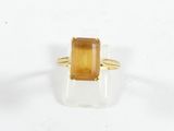 un gros plan d'une bague ornée d'une pierre jaune sur un fond blanc